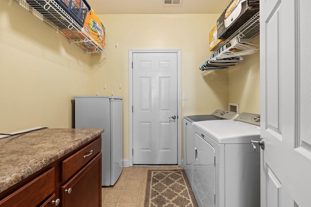 clothes washing area featuring visible vents, washing machine and dryer, and light tile patterned flooring