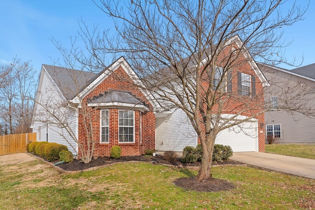 traditional-style home with driveway, fence, a front yard, a garage, and brick siding