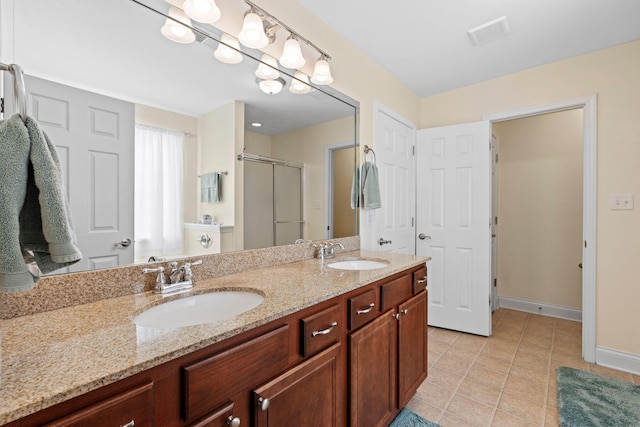 full bath featuring a sink, double vanity, a shower stall, and tile patterned floors