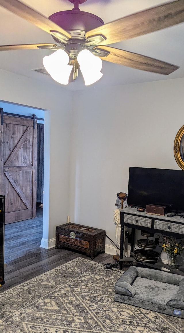 interior space featuring a barn door, ceiling fan, beam ceiling, and dark wood-type flooring