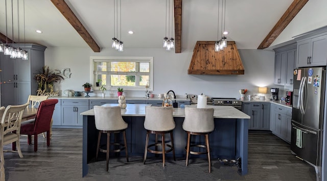 kitchen featuring a kitchen island with sink, dark wood-type flooring, decorative light fixtures, and stainless steel appliances