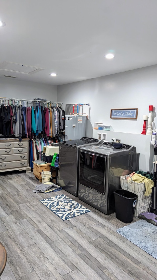 clothes washing area with washing machine and dryer and light wood-type flooring