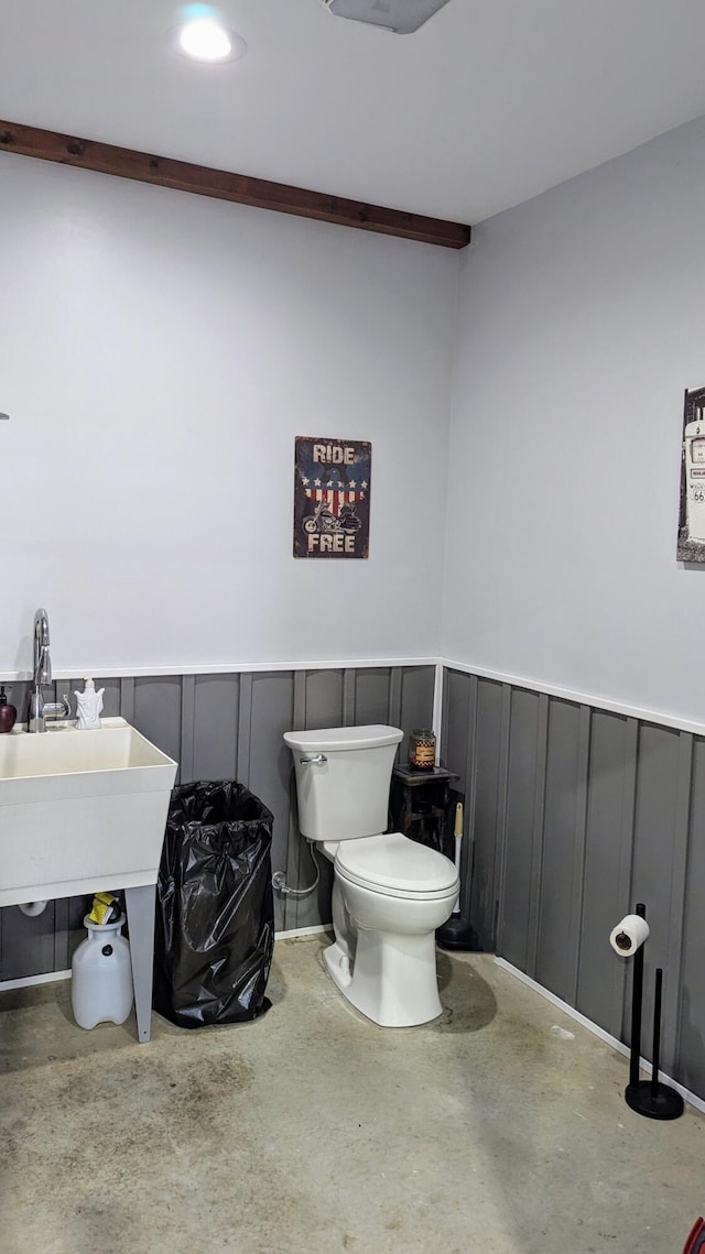 bathroom with concrete flooring, toilet, and sink