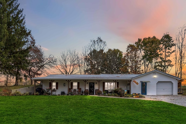 single story home with a garage, a lawn, and a porch