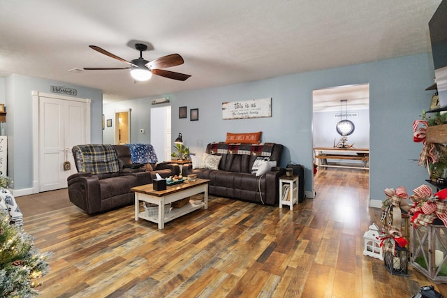 living room featuring ceiling fan, a textured ceiling, and dark hardwood / wood-style flooring