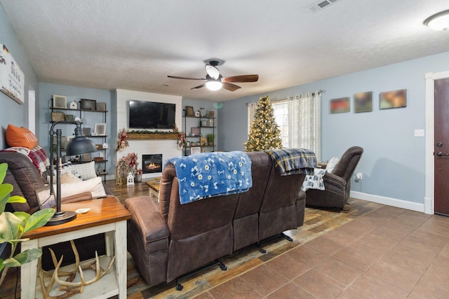 living room featuring ceiling fan, a textured ceiling, and tile patterned floors