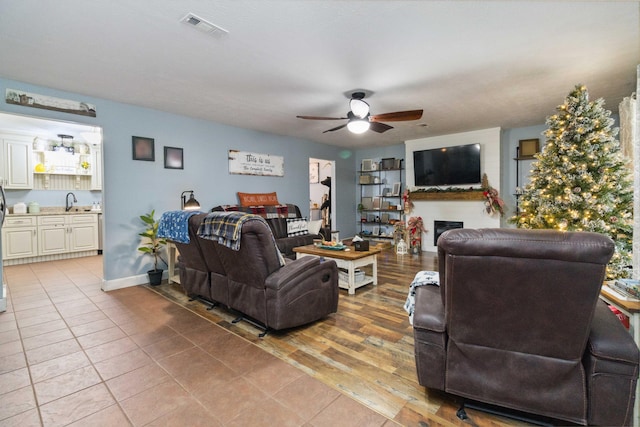 living room featuring ceiling fan, sink, and light wood-type flooring