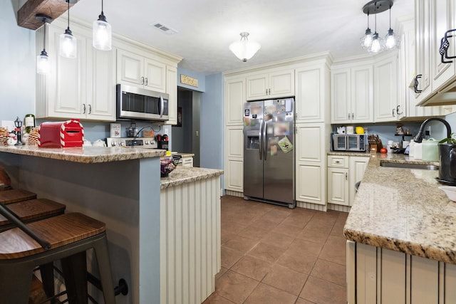 kitchen with a kitchen bar, appliances with stainless steel finishes, and hanging light fixtures