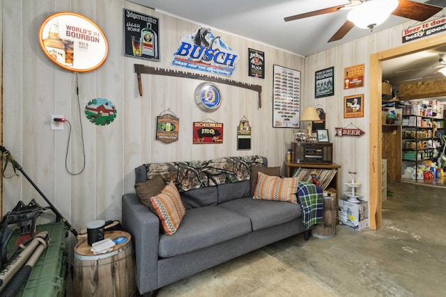 living room featuring ceiling fan, concrete floors, and wooden walls