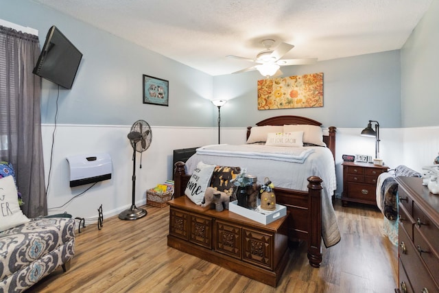 bedroom featuring light wood-type flooring, a textured ceiling, and ceiling fan