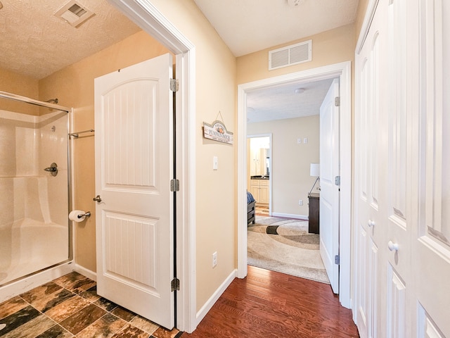 corridor featuring a textured ceiling and dark hardwood / wood-style floors