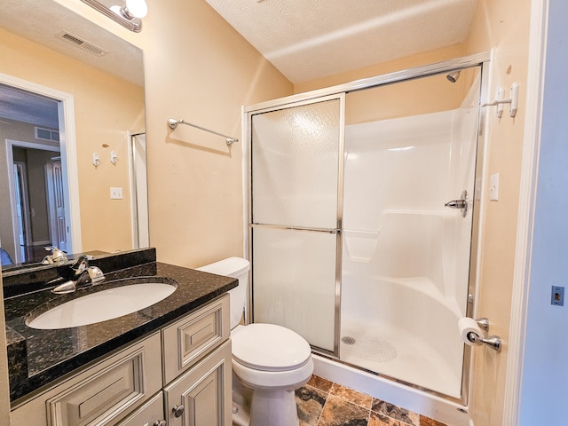 bathroom with vanity, a textured ceiling, toilet, and a shower with door