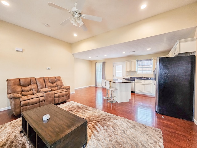 living room with ceiling fan, sink, and dark hardwood / wood-style floors