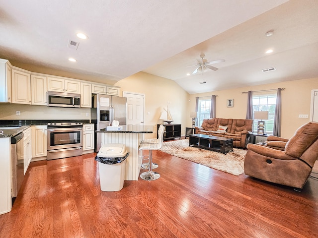 kitchen with stainless steel appliances, lofted ceiling, a center island, hardwood / wood-style floors, and a breakfast bar