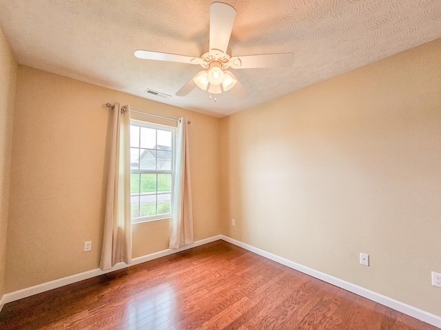 empty room with a textured ceiling, wood-type flooring, and ceiling fan