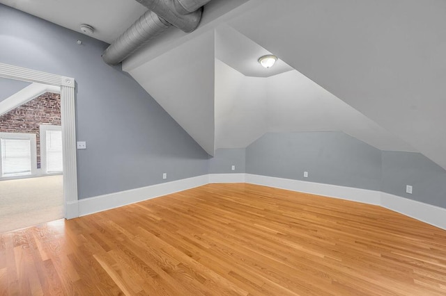 additional living space with light hardwood / wood-style flooring and lofted ceiling