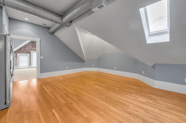 additional living space featuring lofted ceiling with skylight and light hardwood / wood-style floors