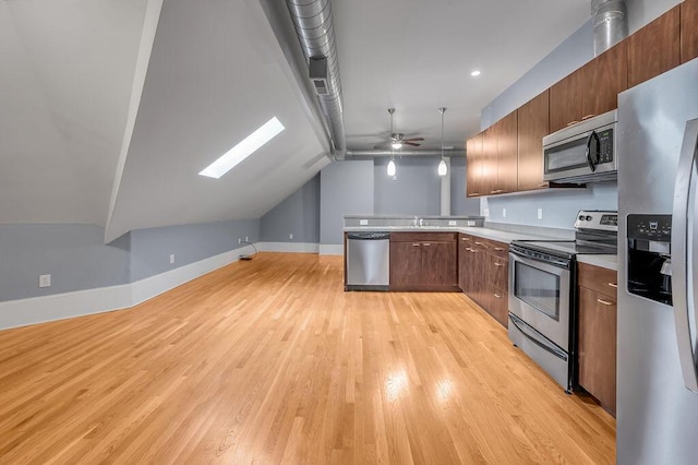 kitchen featuring appliances with stainless steel finishes, vaulted ceiling with skylight, ceiling fan, light hardwood / wood-style flooring, and hanging light fixtures