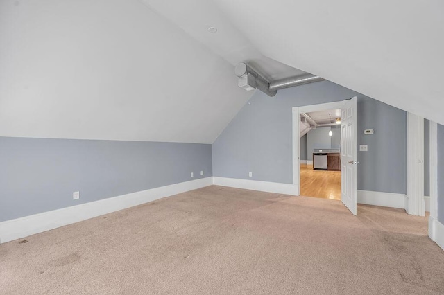 additional living space with light carpet and vaulted ceiling