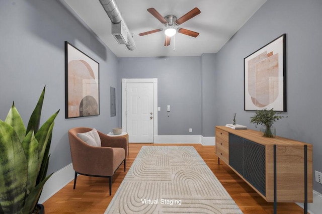 sitting room with hardwood / wood-style flooring, ceiling fan, and electric panel