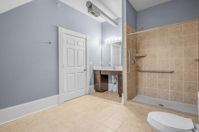 bathroom featuring tile patterned flooring, vanity, toilet, and tiled shower