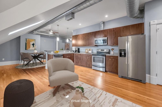 kitchen with kitchen peninsula, appliances with stainless steel finishes, light wood-type flooring, ceiling fan, and hanging light fixtures