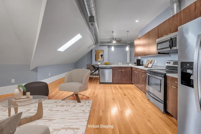 kitchen with ceiling fan, stainless steel appliances, lofted ceiling with skylight, decorative light fixtures, and light wood-type flooring