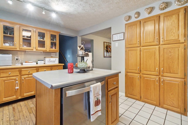 kitchen with a textured ceiling, light tile patterned floors, track lighting, dishwasher, and a center island