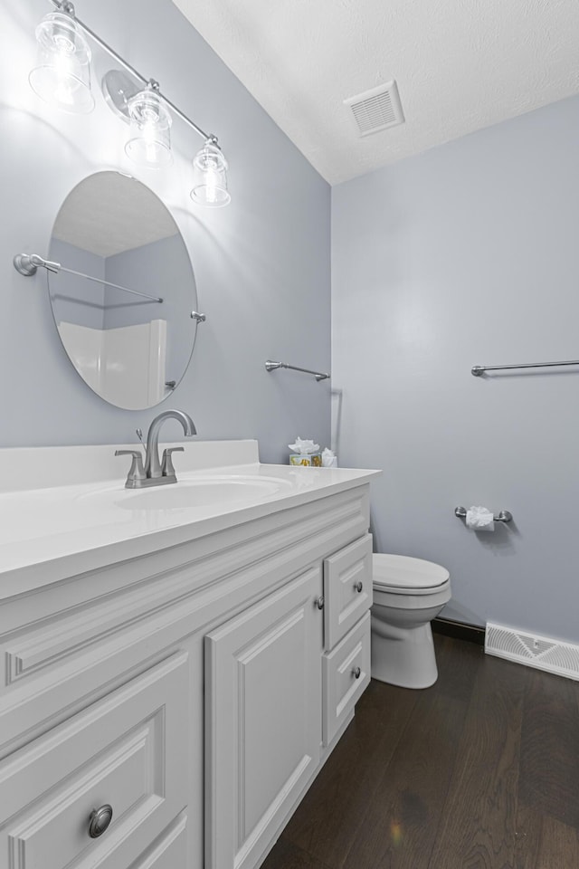 bathroom featuring hardwood / wood-style floors, a shower, vanity, toilet, and a textured ceiling