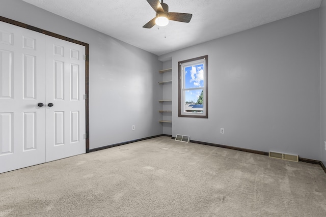 unfurnished bedroom featuring ceiling fan, light colored carpet, a closet, and a textured ceiling