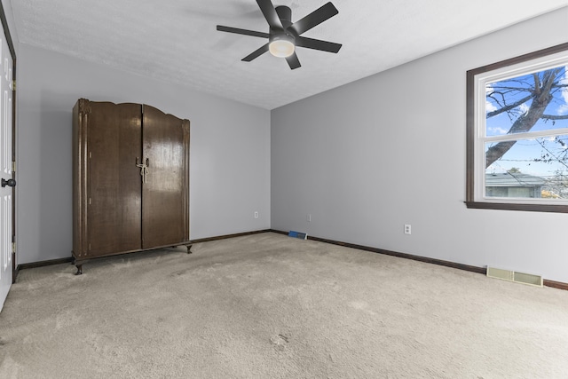 unfurnished bedroom featuring ceiling fan, light colored carpet, and a textured ceiling