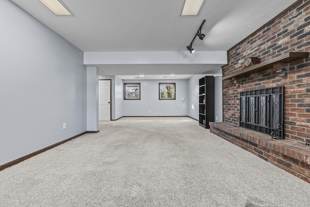 unfurnished living room with track lighting, a brick fireplace, and light carpet