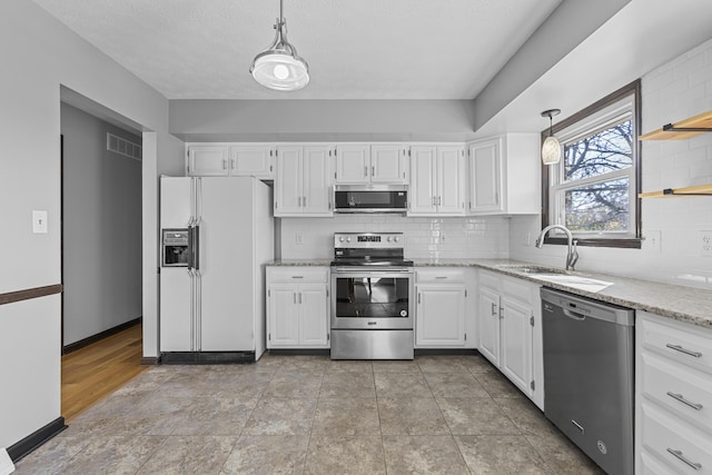 kitchen featuring stainless steel appliances, tasteful backsplash, white cabinets, and decorative light fixtures