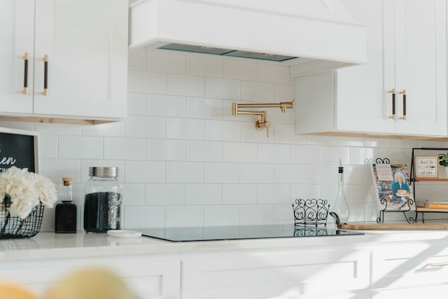 kitchen featuring white cabinets, light stone counters, and ventilation hood