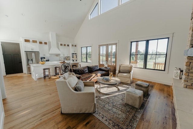 living room featuring light hardwood / wood-style floors, high vaulted ceiling, a wealth of natural light, and sink