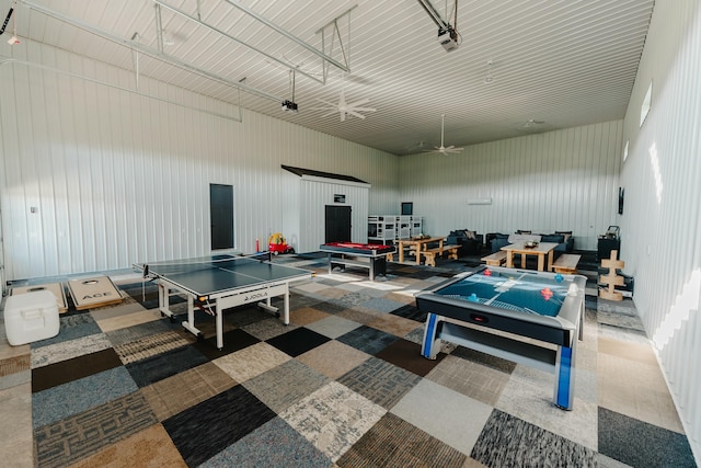 rec room featuring a high ceiling and wooden walls