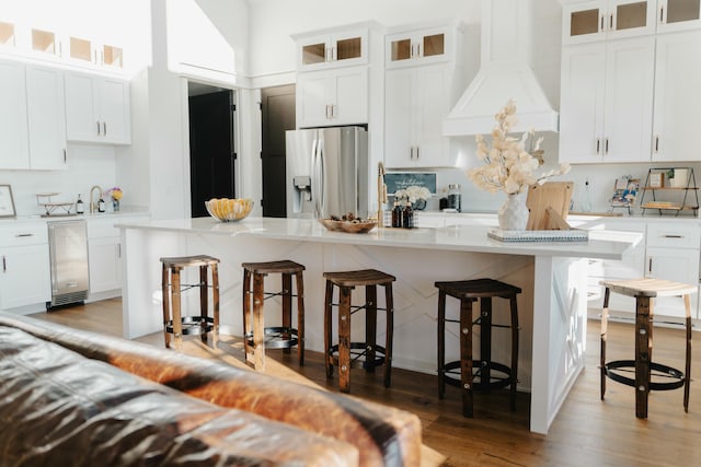 kitchen with a kitchen breakfast bar, stainless steel fridge, and white cabinetry