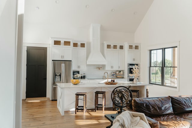 kitchen with white cabinets, a kitchen breakfast bar, stainless steel appliances, and light hardwood / wood-style floors