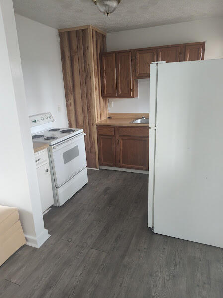 kitchen featuring a textured ceiling, white appliances, dark hardwood / wood-style floors, and sink