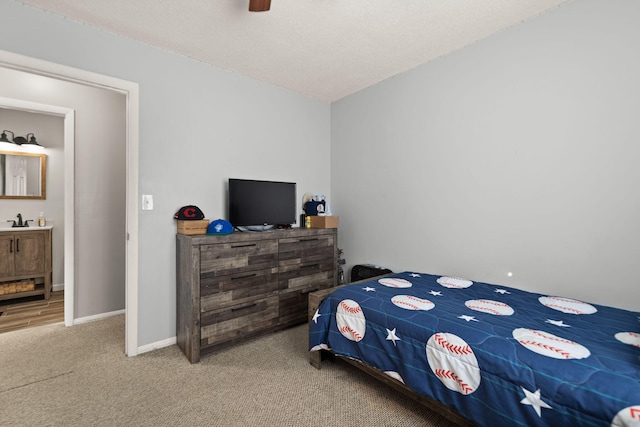 carpeted bedroom with a textured ceiling, ceiling fan, sink, and connected bathroom