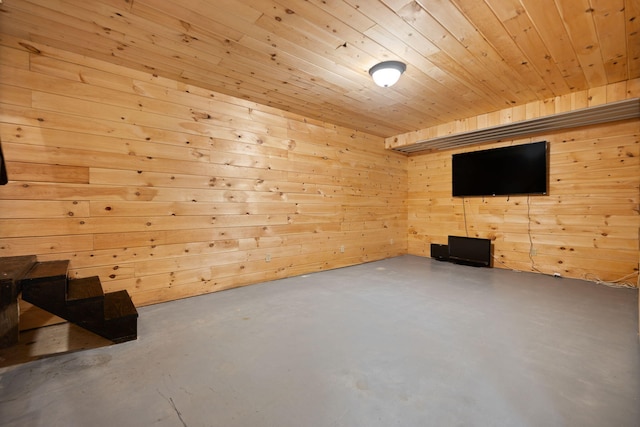 interior space featuring concrete flooring, wooden walls, and wooden ceiling