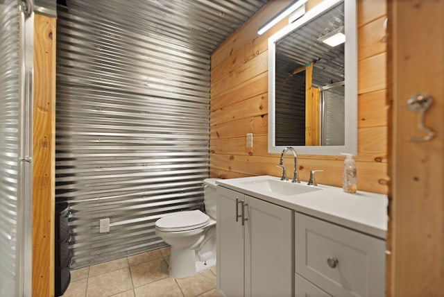 bathroom featuring toilet, wood walls, tile patterned floors, and vanity