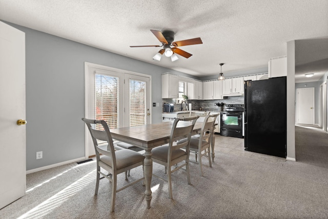 dining area featuring light colored carpet, a textured ceiling, sink, and ceiling fan