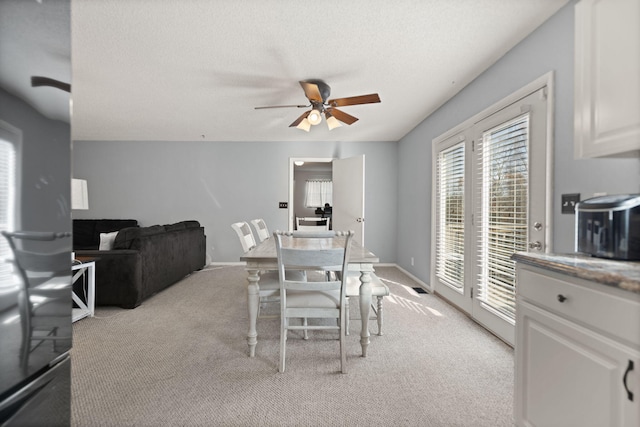 carpeted dining room with ceiling fan and a textured ceiling