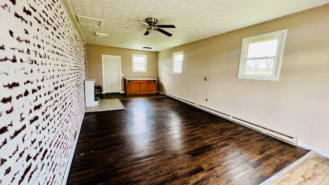 spare room with dark wood-type flooring, ceiling fan, a healthy amount of sunlight, and a baseboard radiator