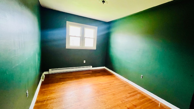 spare room with hardwood / wood-style floors and a baseboard radiator