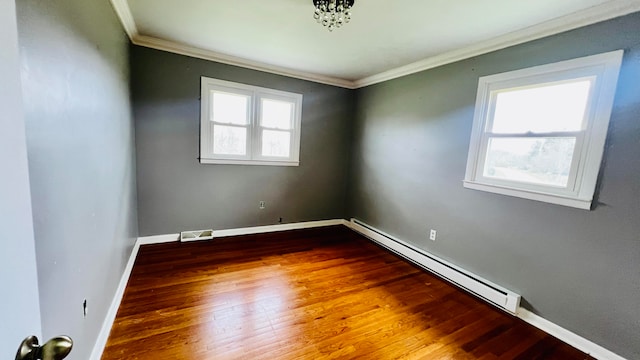 spare room featuring a wealth of natural light, wood-type flooring, a baseboard radiator, and ornamental molding