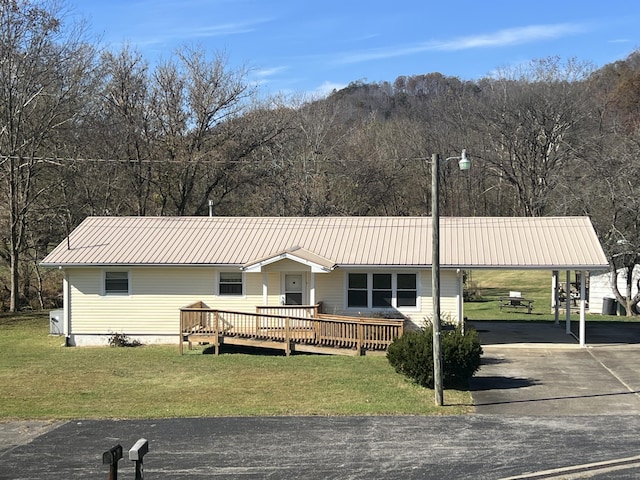 view of front of home with metal roof, a front lawn, a wooden deck, and asphalt driveway