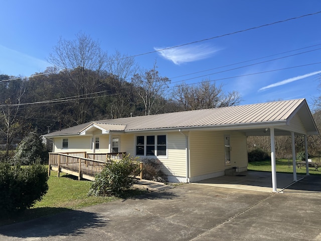 view of front of property featuring driveway, a carport, metal roof, and a wooden deck