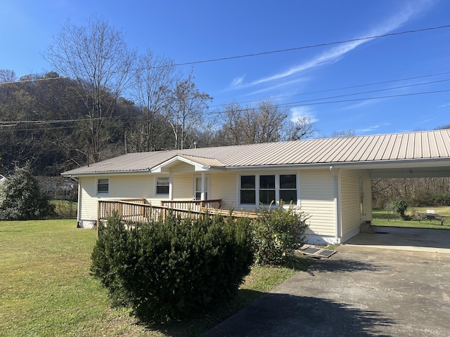 ranch-style house featuring driveway, an attached carport, a front lawn, and metal roof